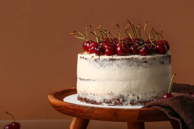 Kırmızı arka planda kirazlı pastayla ahşap tezgah.