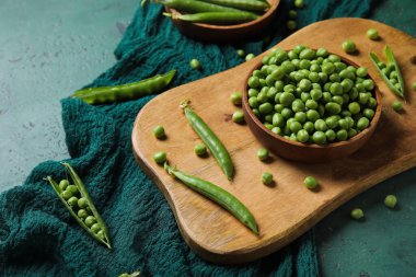 Renkli taze bezelye kabı ve ahşap tahta.
