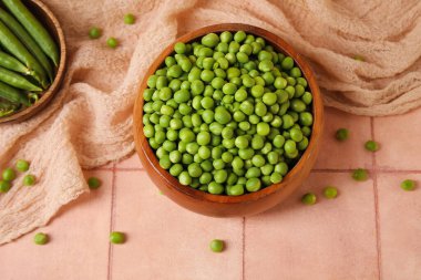 Pembe fayans masasında taze yeşil bezelyeler.