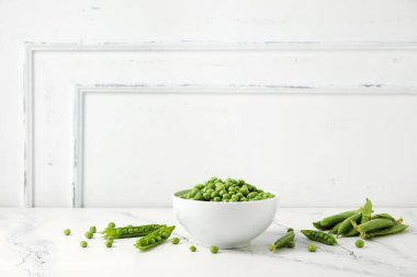 Beyaz arka plan üzerinde taze yeşil bezelye ile kase