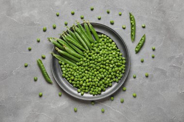 Gri arkaplanda taze yeşil bezelye tabağı