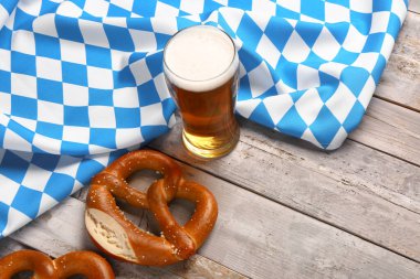 Bavyera bayrağı, bira bardağı ve gri ahşap arka planda kraker.