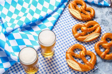 Bavyera bayrağı, biralı kupalar ve mavi arka planda krakerler.