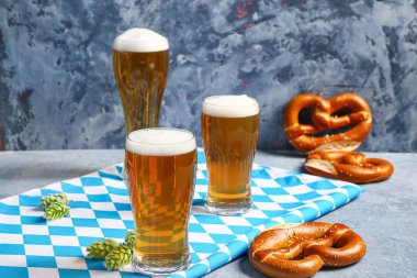 Bavyera bayrağı, biralı kupalar ve mavi arka planda krakerler.
