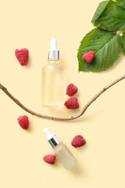 Sarı arka planda kozmetik ahududu yağı şişeleri