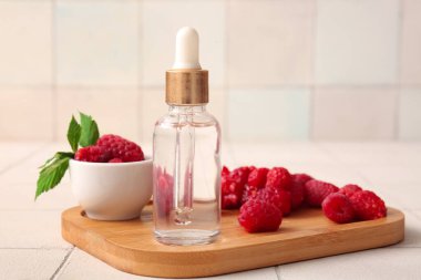 Beyaz fayans zemininde kozmetik ahududu yağı şişesi olan ahşap tahta tahta.