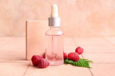 Pembe fayans masasında bir şişe kozmetik ahududu yağı.