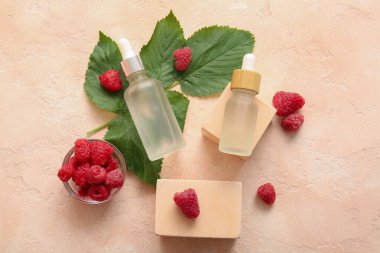 Pembe arka planda kozmetik ahududu yağı şişeleriyle dekoratif podyumlar