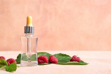 Pembe masada bir şişe kozmetik ahududu yağı.