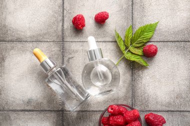 Kozmetik ahududu yağı ve gri kiremit masasında böğürtlen dolu bir kase.