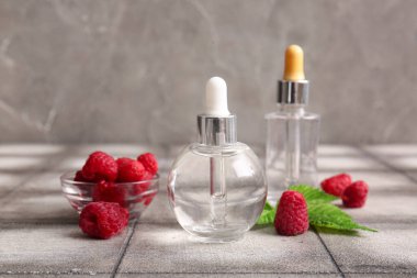 Kozmetik ahududu yağı ve gri kiremit masasında böğürtlen dolu bir kase.