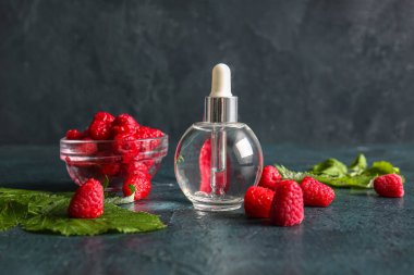 Bir şişe kozmetik ahududu yağı ve koyu arkaplanda böğürtlen.