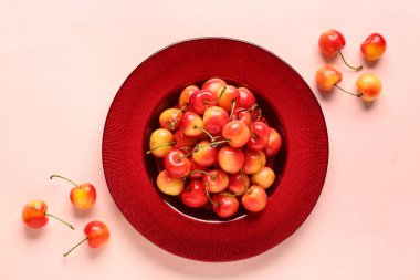 Pembe arka planda sarı kirazlı tatlı bir tabak.
