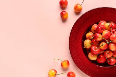 Pembe arka planda sarı kirazlı tatlı bir tabak.