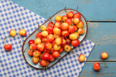 Mavi ahşap zemin üzerinde sarı kirazlı tatlı bir tabak.