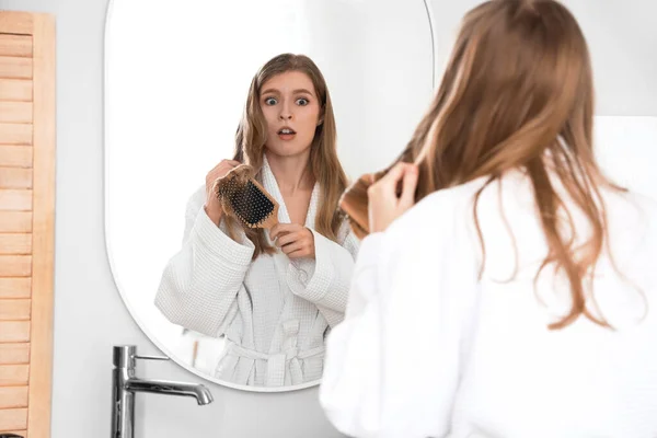 Шокированная Молодая Женщина Проблемой Выпадения Волос Причесывающаяся Возле Зеркала Ванной — стоковое фото