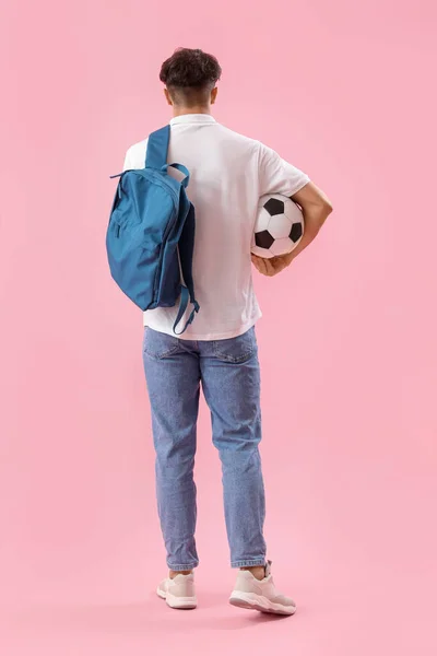 バックパックとサッカーボールを持つ男性学生ピンクの背景 バックビュー — ストック写真