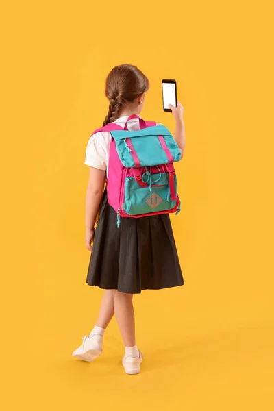 Klein Schoolmeisje Met Rugzak Mobiele Telefoon Gele Achtergrond Achteraanzicht — Stockfoto
