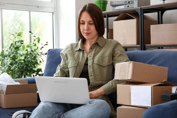 stock image Young woman with parcels using laptop at home