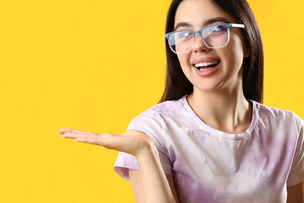 Csinos Fiatal Visel Szemüveget Mutat Valamit Sárga Alapon — Stock Fotó