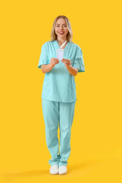 Vrouwelijke Medische Stagiaire Met Badge Gele Achtergrond — Stockfoto