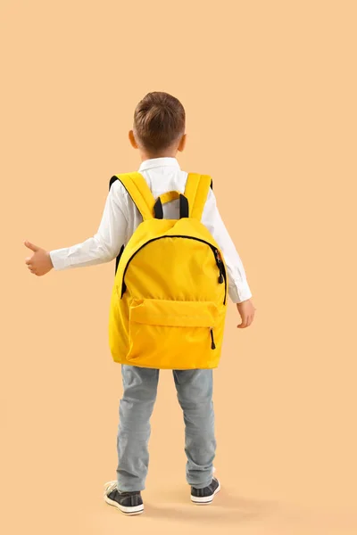 黄色背包的小男生在橙色背景上做着竖起大拇指的手势 后视镜 — 图库照片