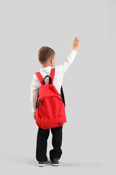 Mały Uczeń Czerwonym Plecakiem Machający Ręką Szarym Tle Widok Tyłu — Zdjęcie stockowe