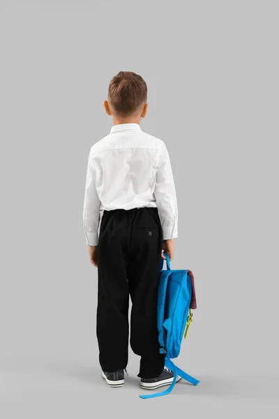 Kleine Schooljongen Met Blauwe Rugzak Grijze Achtergrond Achteraanzicht — Stockfoto