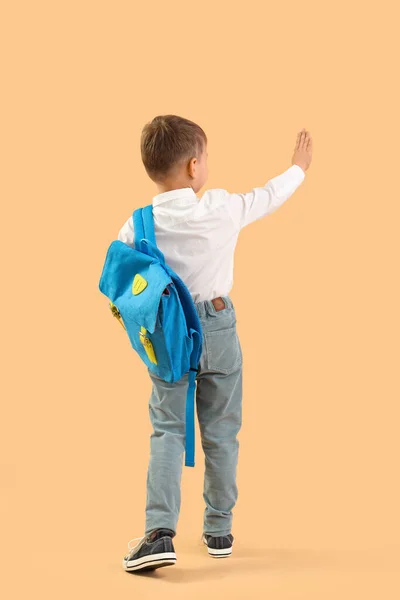 小男孩 背着背包手拿着橙色背景的手 后视镜 — 图库照片