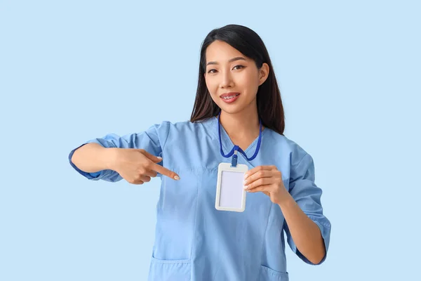Female Asian Medical Intern Pointing Badge Blue Background — Stock Photo, Image