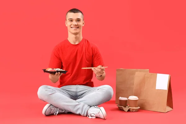 Young Man Eating Tasty Sushi Red Background — Stock Photo, Image