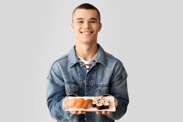 軽い背景でおいしい寿司を持つ若い男 — ストック写真