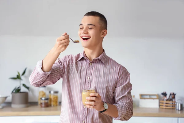 Young Man Eating Tasty Nut Butter Kitchen — Stock Photo, Image