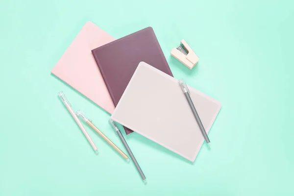 不同的彩色笔记本 蓝绿色背景的钢笔和订书机 — 图库照片