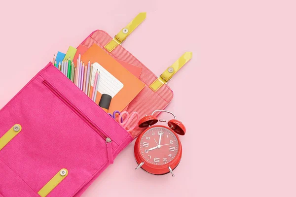 バックパック付き目覚まし時計と異なる文房具ピンクの背景 — ストック写真