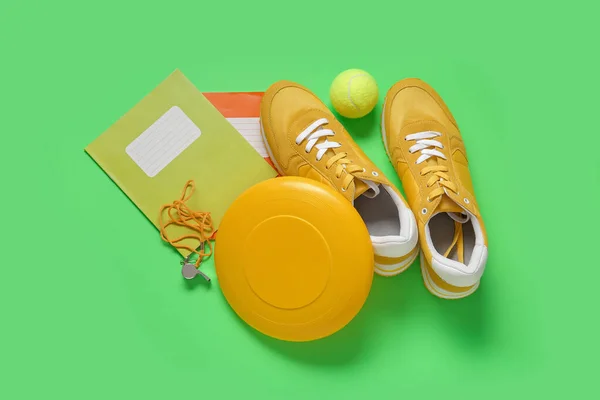 Sneakers Frisbee Tennis Ball Whistle Notebooks Green Background — Stock Photo, Image