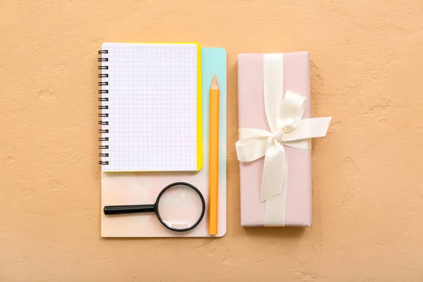 装有笔记本和橙色背景放大镜的礼品盒 — 图库照片
