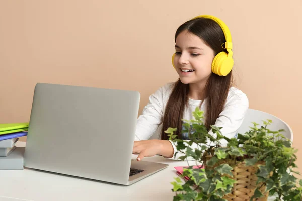 Κοριτσάκι Ακουστικά Φορητό Υπολογιστή Κάνει Μαθήματα Στο Τραπέζι Μπεζ Φόντο — Φωτογραφία Αρχείου