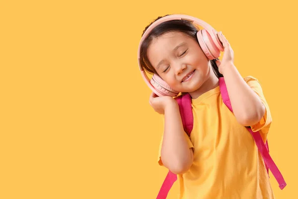 在黄色背景下听音乐的小女孩 — 图库照片