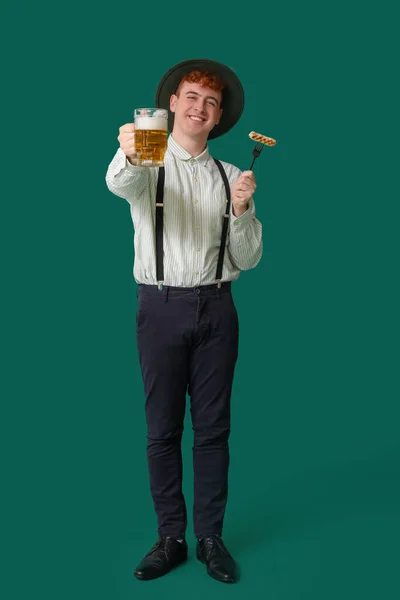 Junger Mann Tracht Mit Bier Und Wurst Auf Grünem Hintergrund — Stockfoto