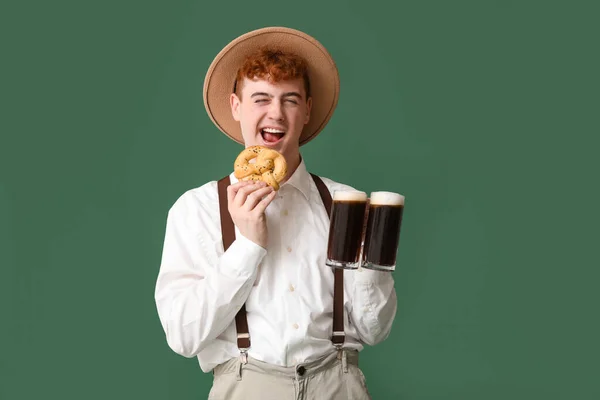 Junger Mann Tracht Mit Bier Und Brezel Auf Grünem Hintergrund — Stockfoto
