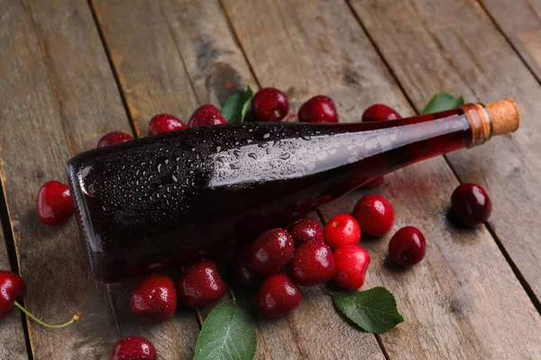 stock image Bottle with sweet cherry liqueur on wooden background