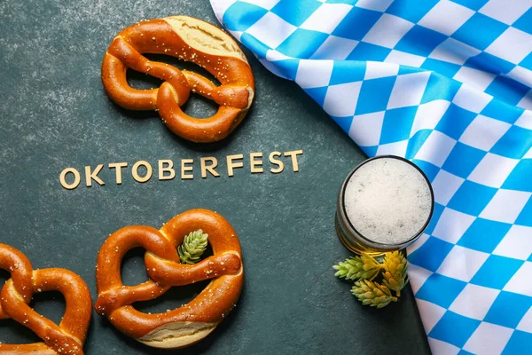 单词Oktoberfest 巴伐利亚国旗 啤酒杯和蓝色背景的椒盐卷饼 — 图库照片