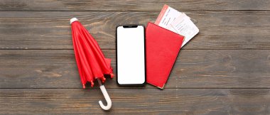 Pasaportlu cep telefonu, biletler ve koyu ahşap arka planda küçük şemsiyeli. Hava tahmini kavramı