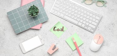 Kelime GOAL, kırtasiye, bilgisayar klavyesi, cep telefonu ve grunge arkaplanda gözlük içeren yapışkan bir not