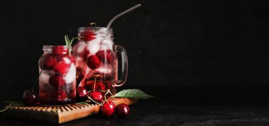 Mason kavanozları siyah zemin üzerinde vişneli limonata ve metin için yer var.