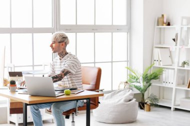 Ofiste bilgisayarla çalışan dövmeli grafik tasarımcısı