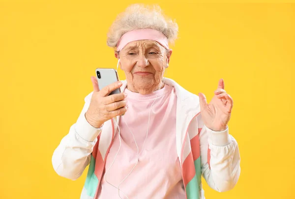 Спортивная Пожилая Женщина Наушниками Мобильным Телефоном Желтом Фоне — стоковое фото