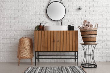 Lavabo lavabosu ve ahşap dolapta banyo aksesuarları olan banyo.