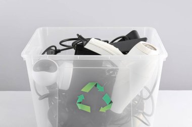 Gri arka planda farklı ev aletleri olan geri dönüşüm kutusu